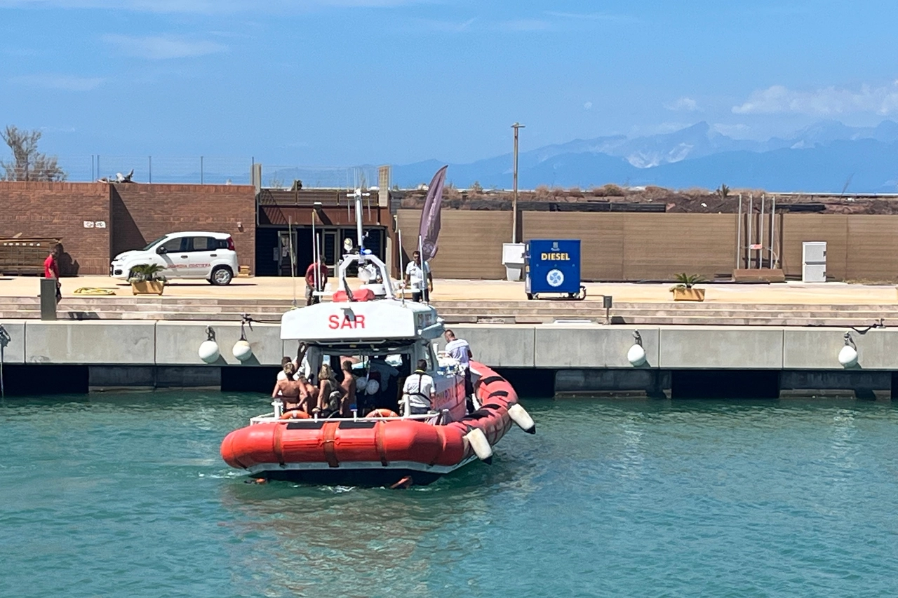 Le persone a bordo della barca andata a fuoco mentre vengono riportate a Marina di Pisa dalla guardia costiera