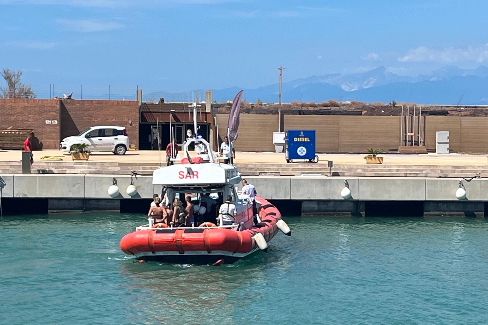 Le persone a bordo della barca andata a fuoco mentre vengono riportate a Marina di Pisa dalla guardia costiera