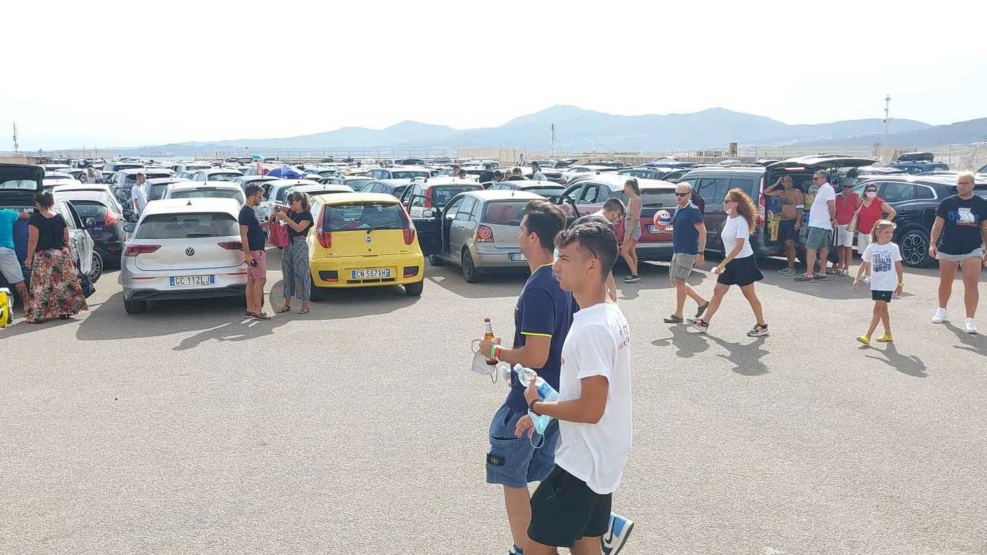 La distesa delle auto e le persone in attesa sul piazzale del porto in Sardegna